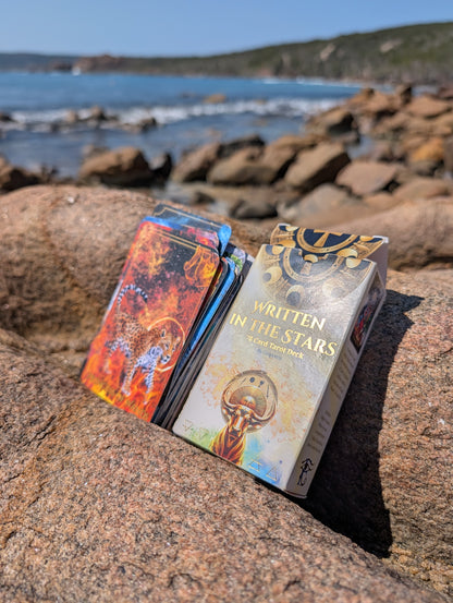 Written in the Stars 78 Card Tarot Deck and box by Emporos resting on coastal rocks — eco-conscious tarot made in Devon and Cornwall, designed to travel Australia