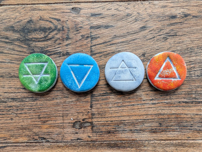 Four colorful stones with engraved symbols on a wooden surface